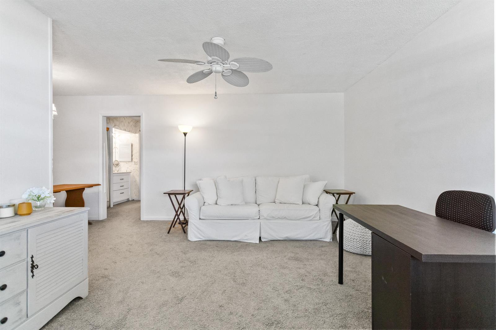 A living room features a white sofa, a dark desk, and a ceiling fan — 30 SE 13th Street # B3, Boca Raton FL 33432, BOCA RATON, FL
