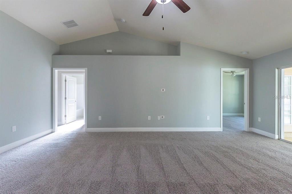 A spacious room with gray walls, vaulted ceilings, carpeted flooring, and two doorways — 3401 EVERETT TERRACE, NORTH PORT, FL
