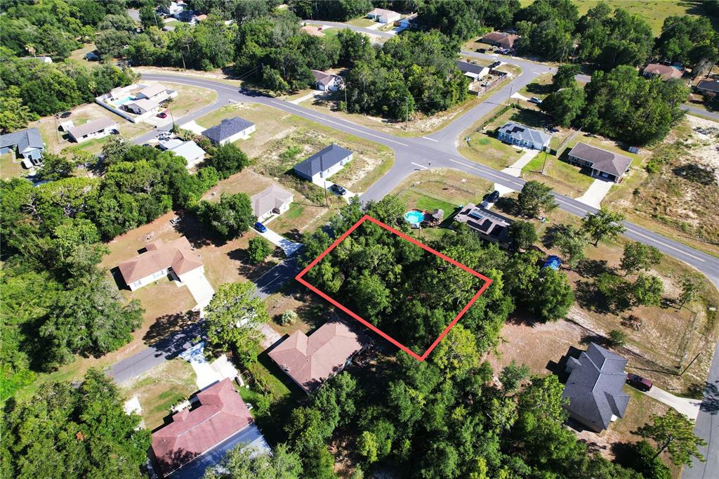 An aerial view shows a vacant, wooded residential lot outlined in red — BAHIA COURT TERRACE, OCALA, FL