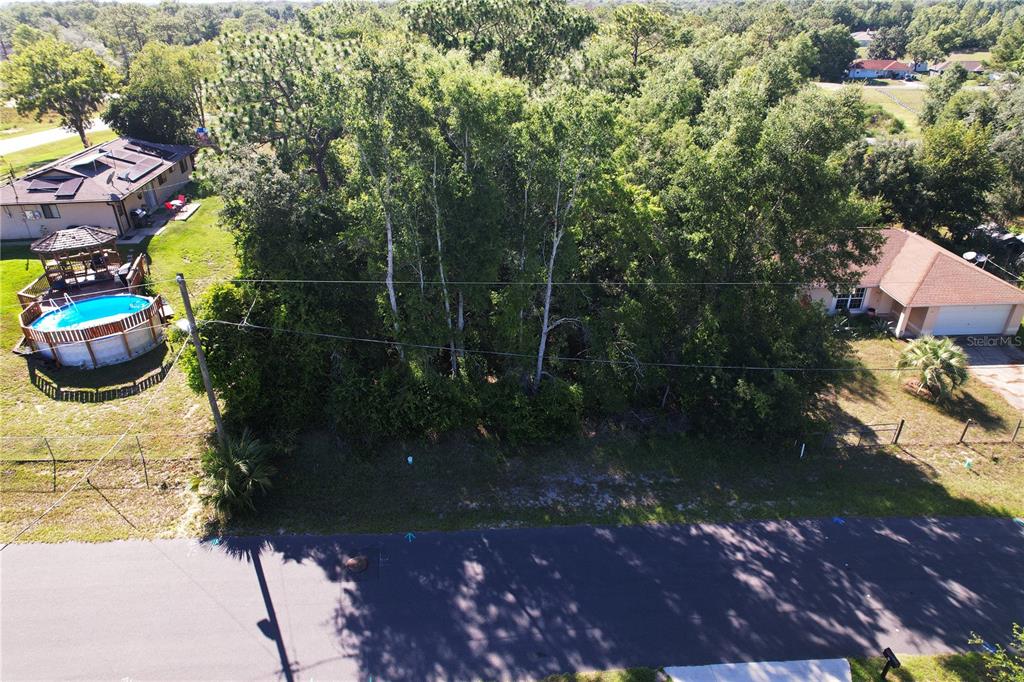 An aerial view shows a vacant, wooded lot situated between two residential houses — BAHIA COURT TERRACE, OCALA, FL