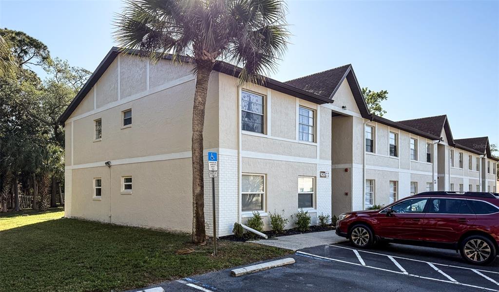 A two-story apartment building with beige stucco siding and a red SUV parked in front — 420 BANANA CAY DRIVE UNIT A, SOUTH DAYTONA, FL