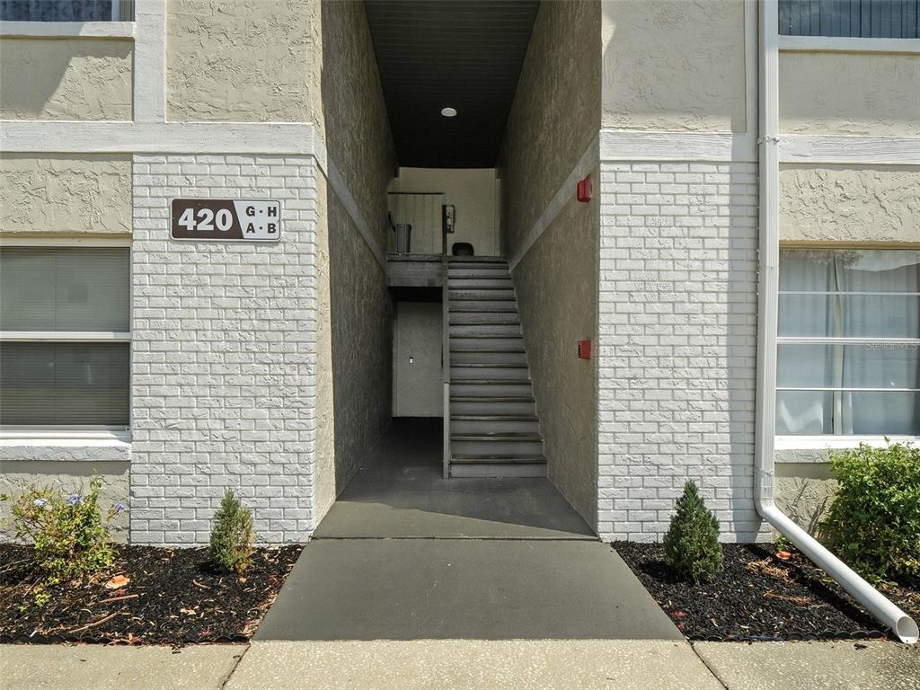 The exterior of a multi-unit residential building features a central staircase leading to upper levels — 420 BANANA CAY DRIVE UNIT A, SOUTH DAYTONA, FL