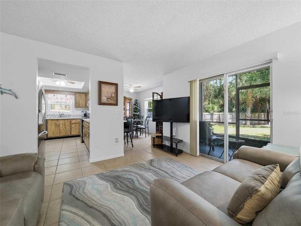 A living room with tile floors, a television, and a sliding door to a patio — 420 BANANA CAY DRIVE UNIT A, SOUTH DAYTONA, FL