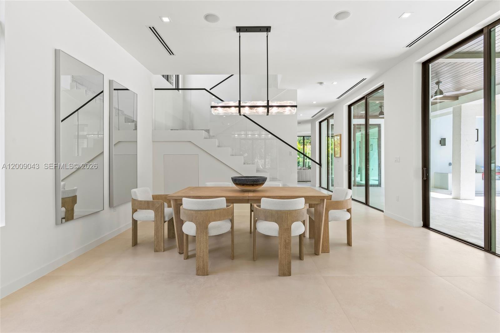A modern dining room features a wooden table, white chairs, and a glass staircase — 730 Zamora Ave, Coral Gables FL 33134, CORAL GABLES, FL