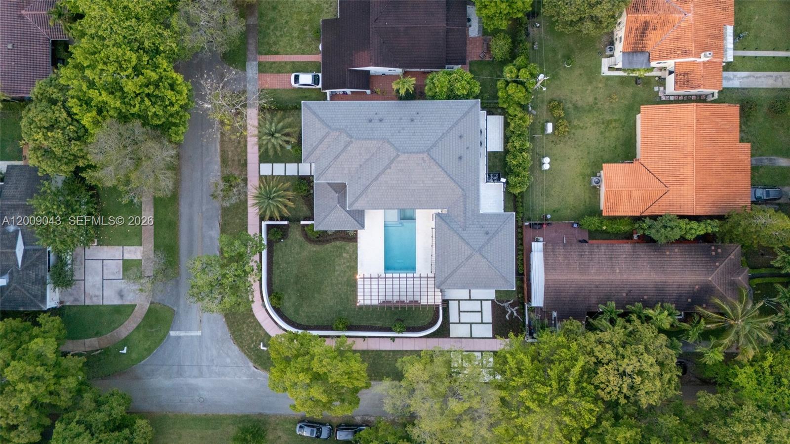 An aerial view shows a house with a grey roof, a swimming pool, and landscaping — 730 Zamora Ave, Coral Gables FL 33134, CORAL GABLES, FL
