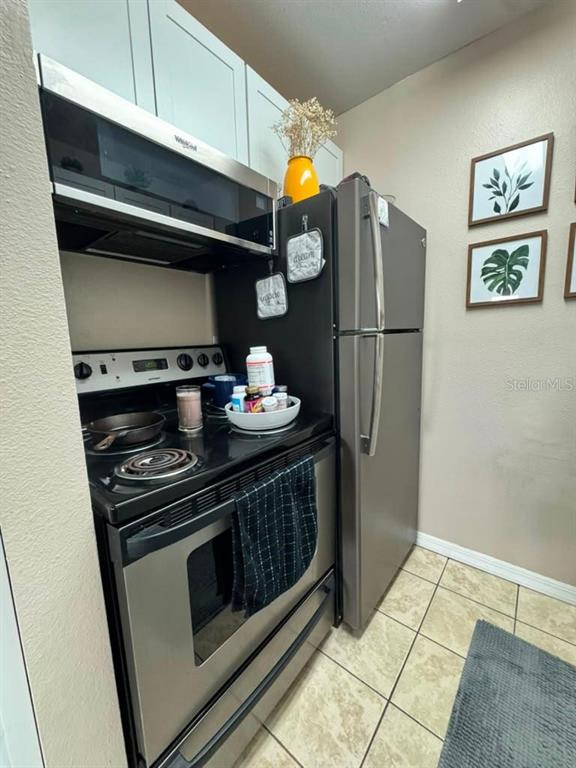 A kitchen features stainless steel appliances, light-colored cabinets, and framed botanical wall art — 4140 DOLPHIN DRIVE, TAMPA, FL