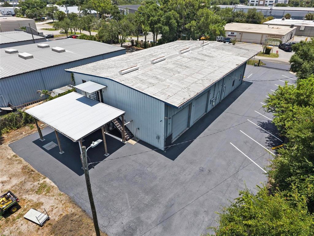 An aerial view shows a metal warehouse building with a covered parking area and lot — 5021 W NASSAU STREET, TAMPA, FL