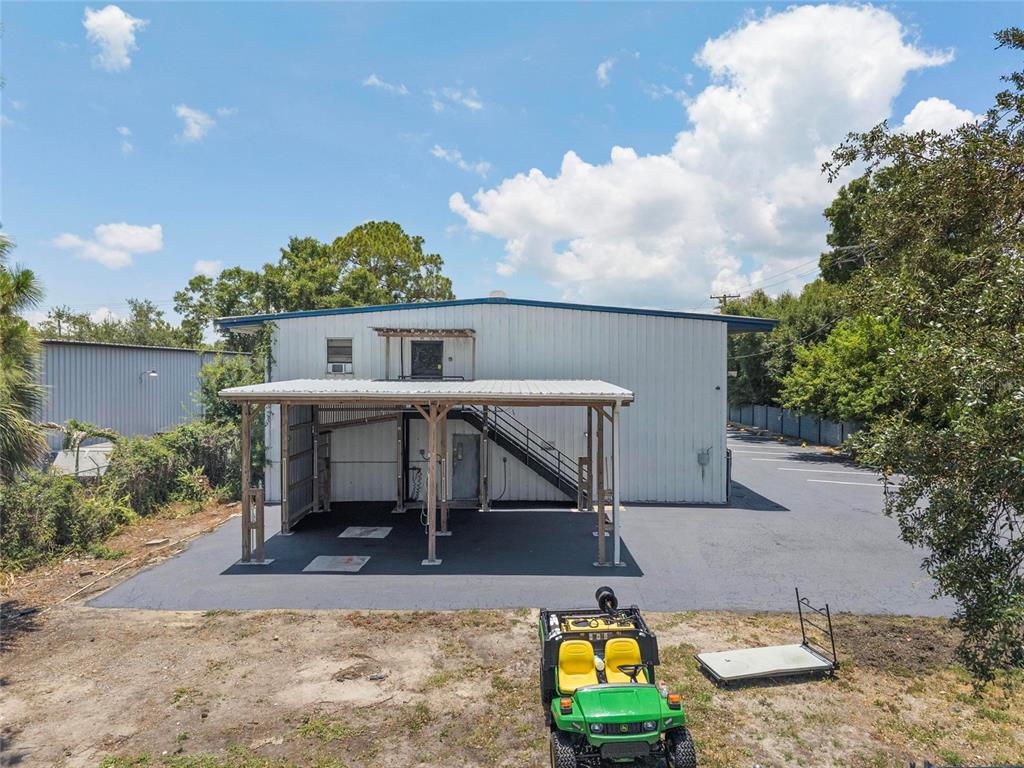 An exterior view of a metal building with a covered parking area and outdoor stairs — 5021 W NASSAU STREET, TAMPA, FL