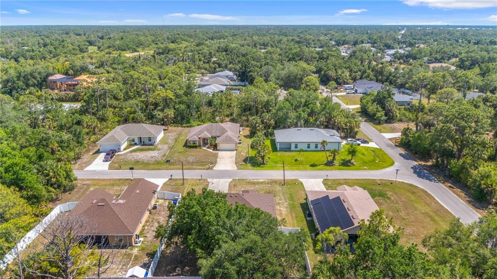 An aerial view shows several single-family homes surrounded by trees and a paved road — 3680 CHANNING AVENUE, NORTH PORT, FL