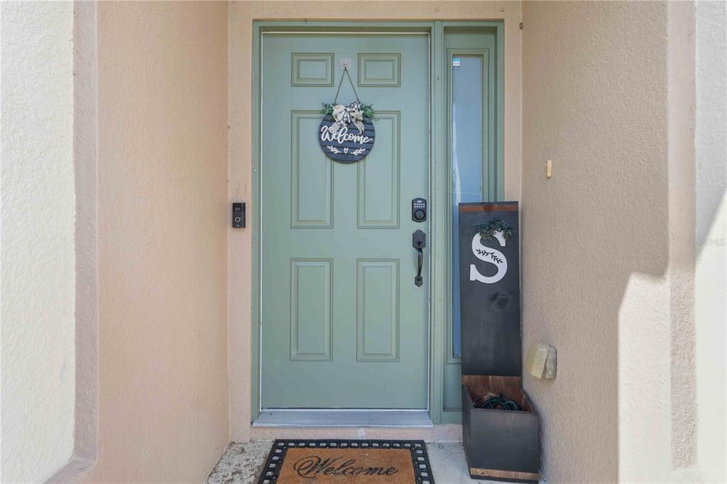 A light green front door with a welcome sign and a letter S porch sign — 3680 CHANNING AVENUE, NORTH PORT, FL