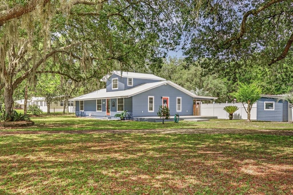 A blue two-story house with a white roof sits on a large, grassy lot — 121 DAREN DRIVE, PALATKA, FL