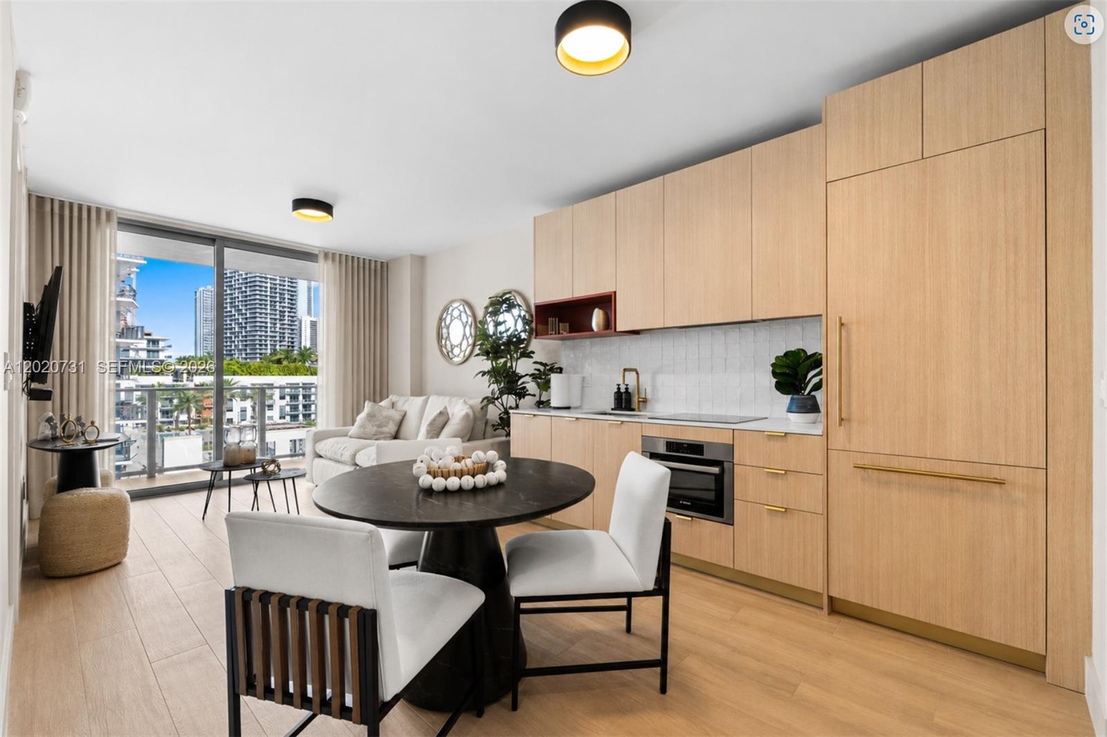 A modern kitchen and dining area with light wood cabinetry, a round table, and balcony — 90 NE 32 # 905, Miami FL 33137, MIAMI, FL
