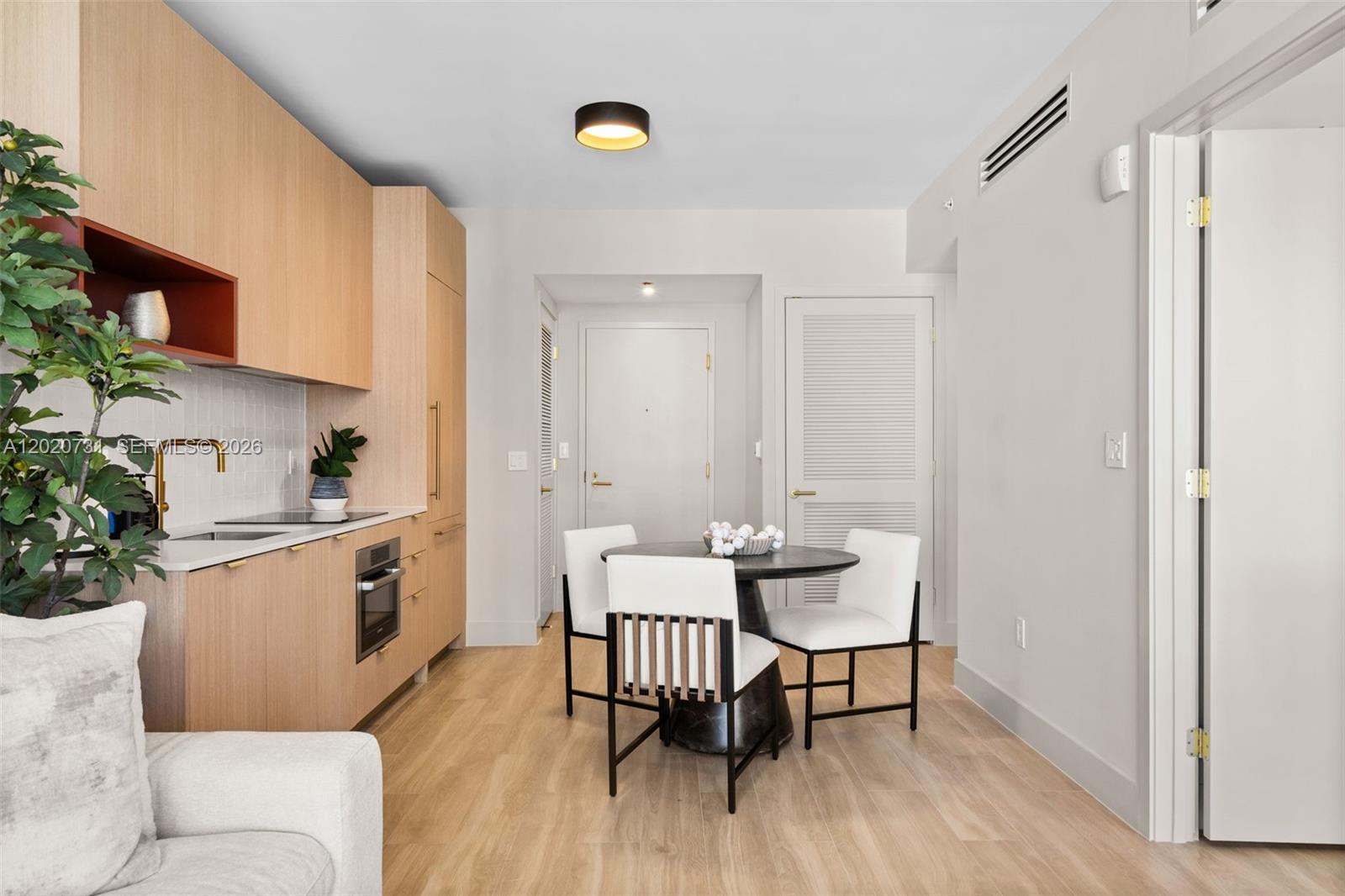 A modern kitchen with light wood cabinetry features a small dining table and chairs — 90 NE 32 # 905, Miami FL 33137, MIAMI, FL