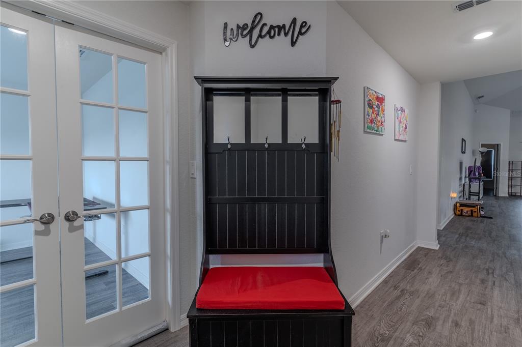 A black hall tree with a red cushion sits in a hallway near French doors — 629 FAIRHOPE DRIVE, POLK CITY, FL