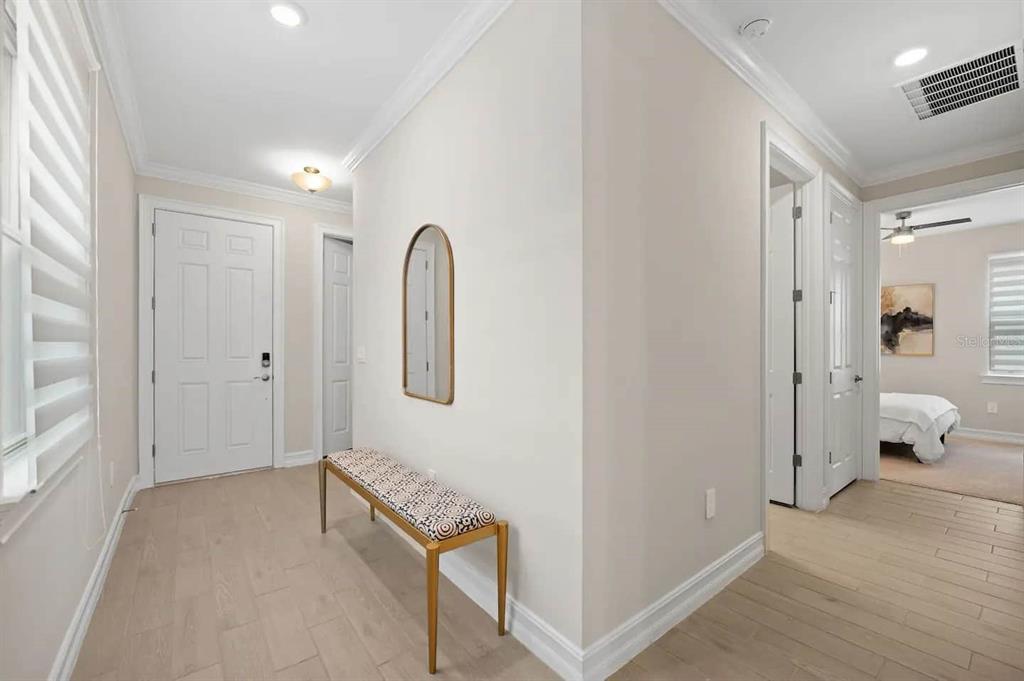 A bright entryway features light wood-look flooring, a patterned bench, and an arched wall mirror — 245 TERAMO WAY, NOKOMIS, FL