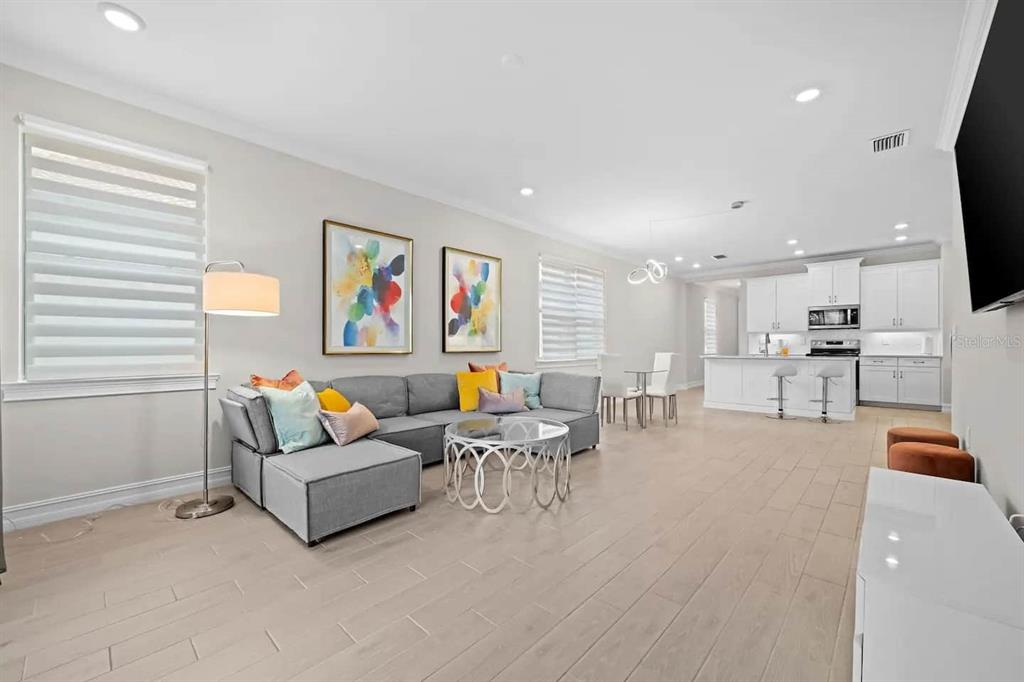 A modern open-concept living room and kitchen featuring light wood flooring and gray furniture — 245 TERAMO WAY, NOKOMIS, FL