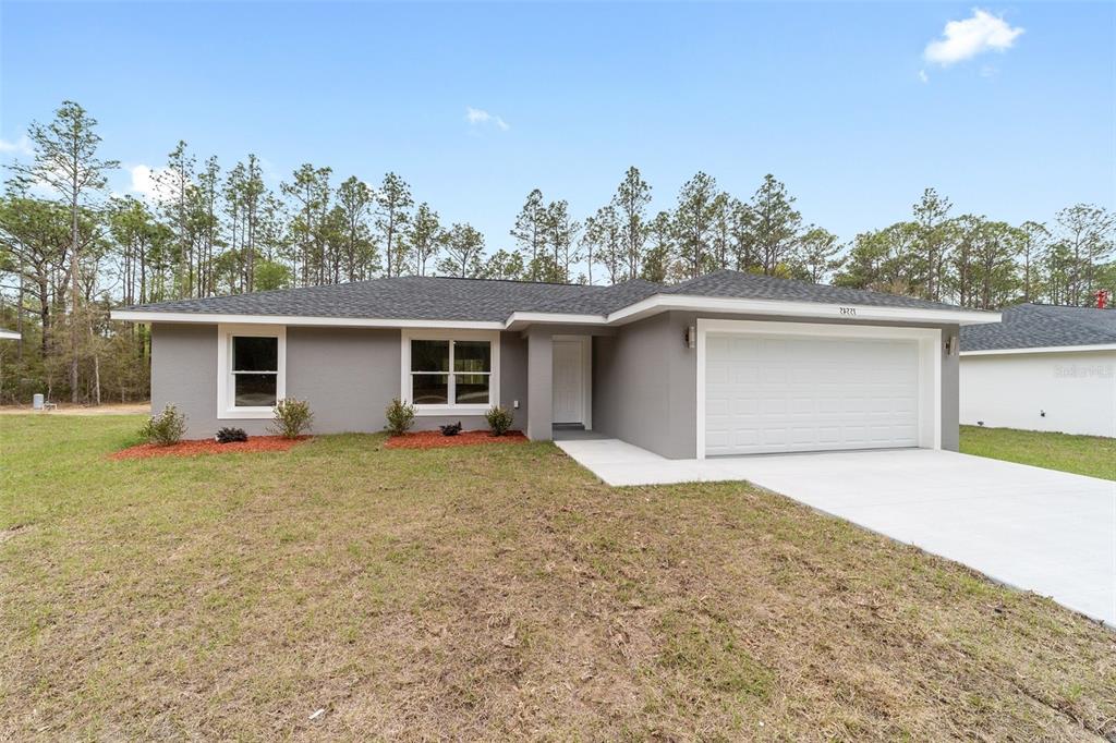 A single-story gray house with a white garage door and a concrete driveway — 24272 NW ASPEN LANE, DUNNELLON, FL