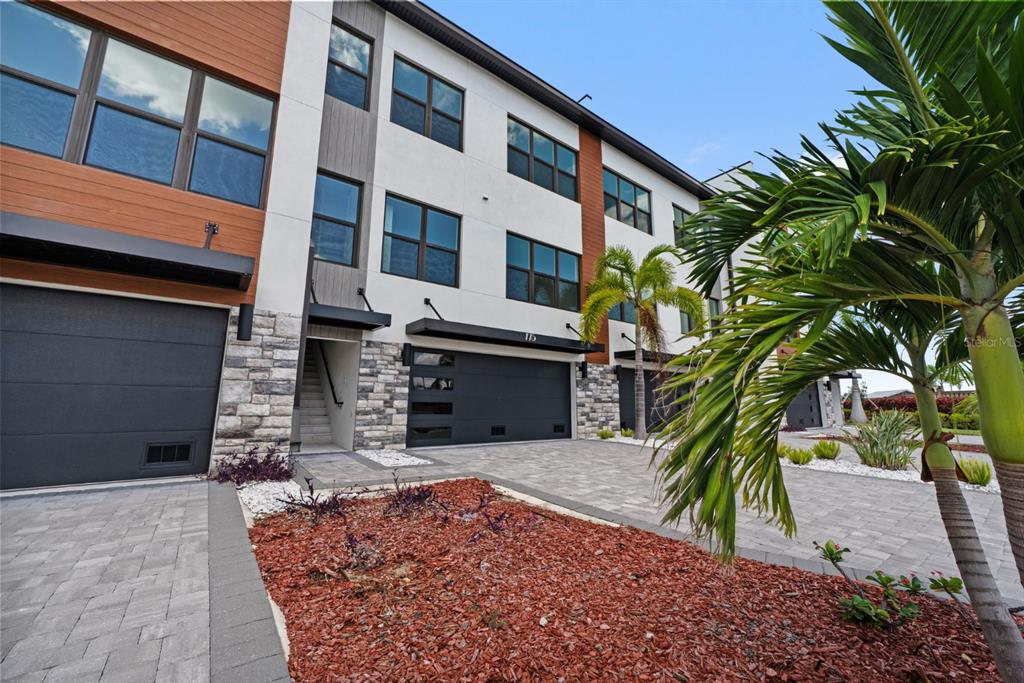 A modern three-story townhouse exterior with a stone facade, garage, and a palm tree — 772 GRAN KAYMEN WAY, APOLLO BEACH, FL