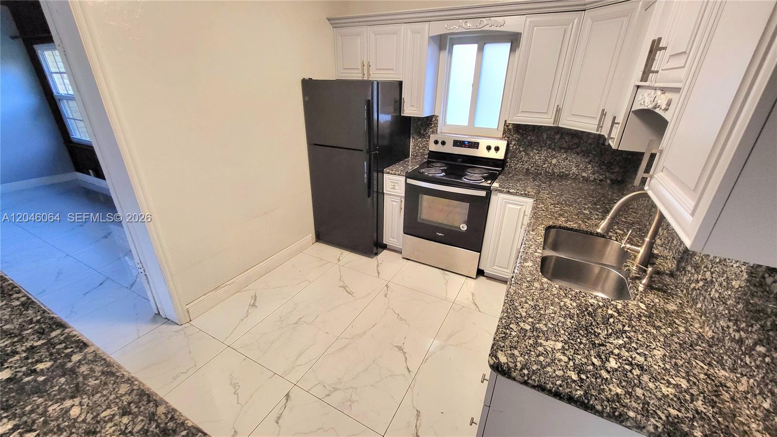 A kitchen features white cabinets, granite countertops, a stainless steel stove, and a black refrigerator — 720 NE 5th St # 1, Hallandale Beach FL 33009, HALLANDALE BEACH, FL
