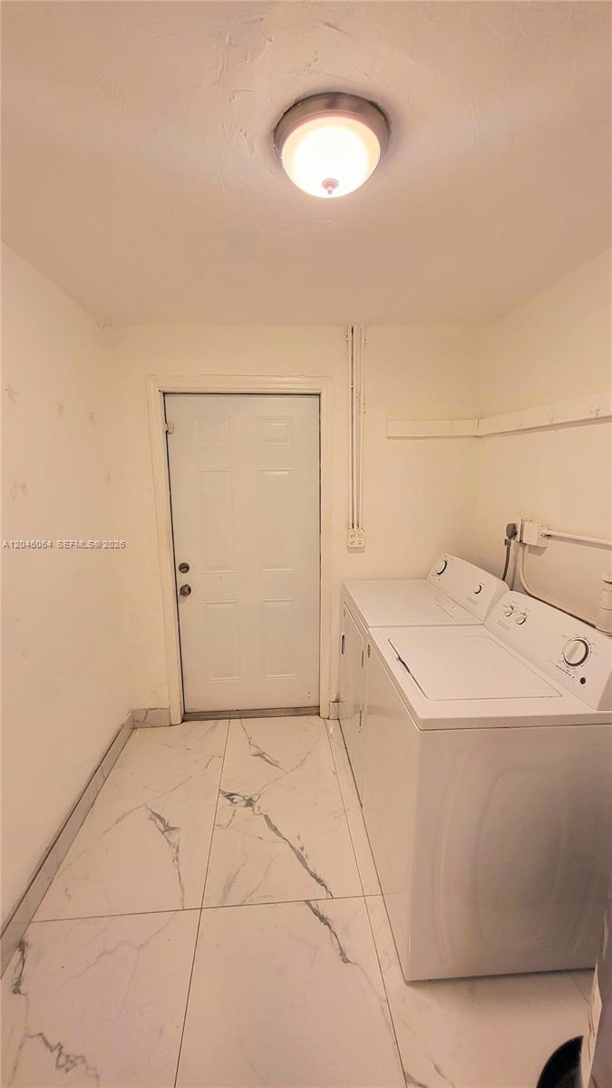 A laundry room features white tile flooring, a white door, and a side-by-side washer and dryer — 720 NE 5th St # 1, Hallandale Beach FL 33009, HALLANDALE BEACH, FL