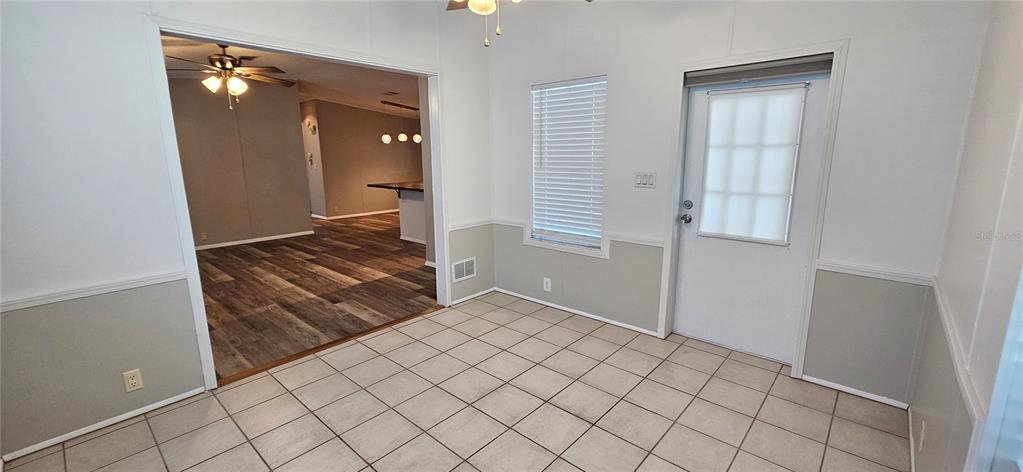 A dining area features tiled flooring, two-tone walls, a ceiling fan, and a glass-paneled door — 8410 WAGON WHEEL CIRCLE, NORTH FORT MYERS, FL