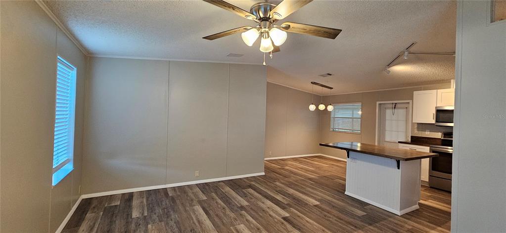 An open-concept living and kitchen area features wood-look flooring, a ceiling fan, and a kitchen island — 8410 WAGON WHEEL CIRCLE, NORTH FORT MYERS, FL