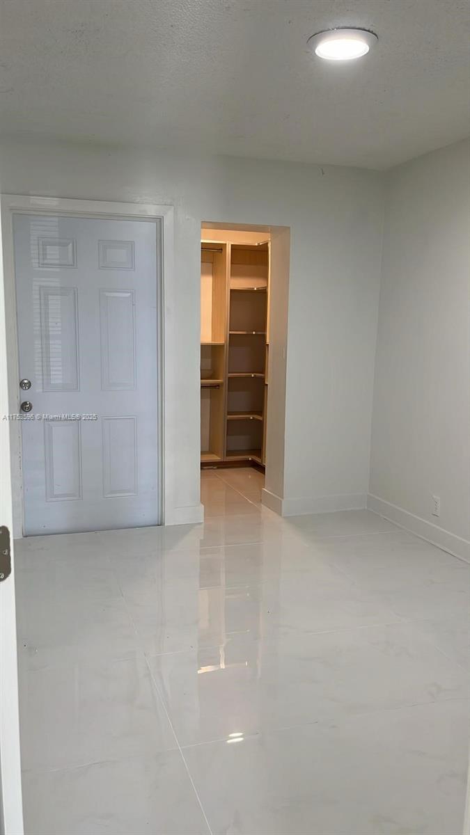 A room with white tile floors, a white door, and an open walk-in closet — 6051 Arthur St # 14, Hollywood FL 33024, HOLLYWOOD, FL
