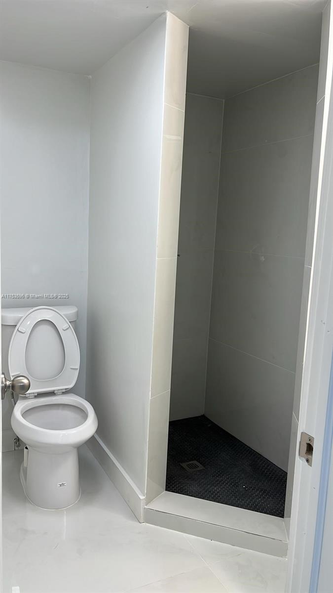 A bathroom features a white toilet next to a walk-in shower with gray tiled walls — 6051 Arthur St # 14, Hollywood FL 33024, HOLLYWOOD, FL