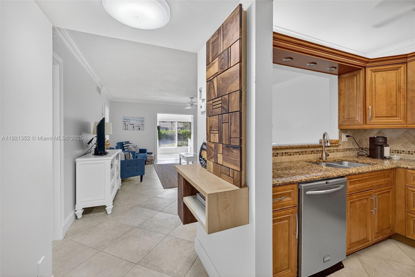 A kitchen with wood cabinets and granite countertops opens into a living area with tile — 5681 SW 2nd Ct # 117, Margate FL 33068, MARGATE, FL