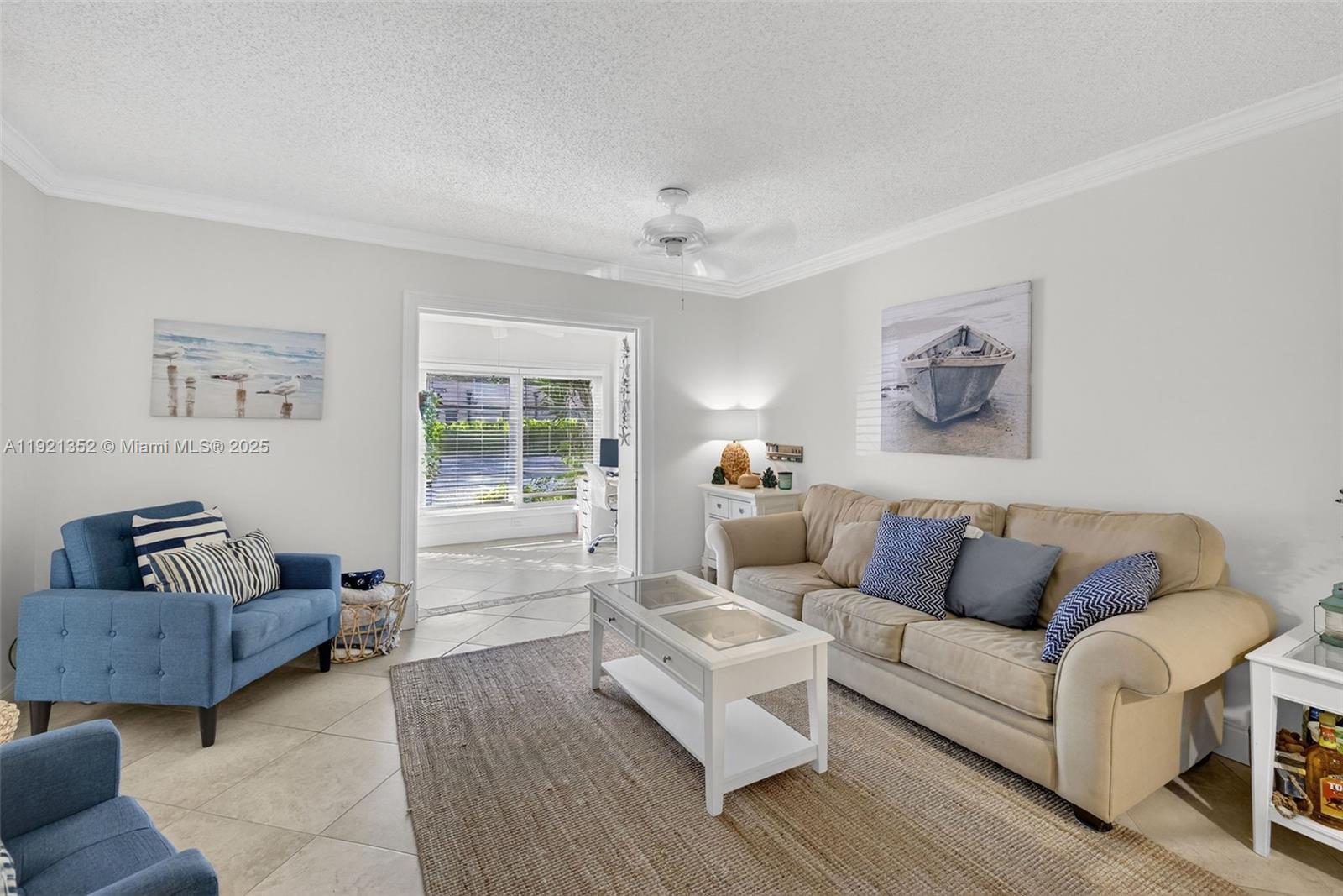 A living room features a beige sofa, blue armchairs, a white coffee table, and artwork — 5681 SW 2nd Ct # 117, Margate FL 33068, MARGATE, FL