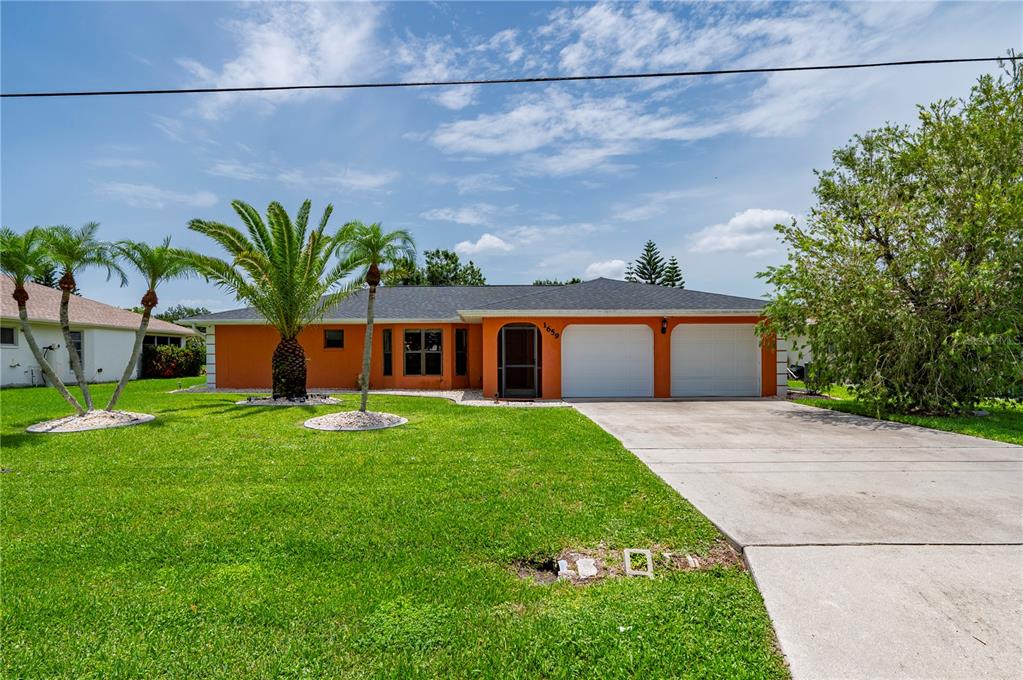A single-story orange house with a two-car garage and palm trees in the front yard — 1659 BLUE LAKE CIRCLE, PUNTA GORDA, FL