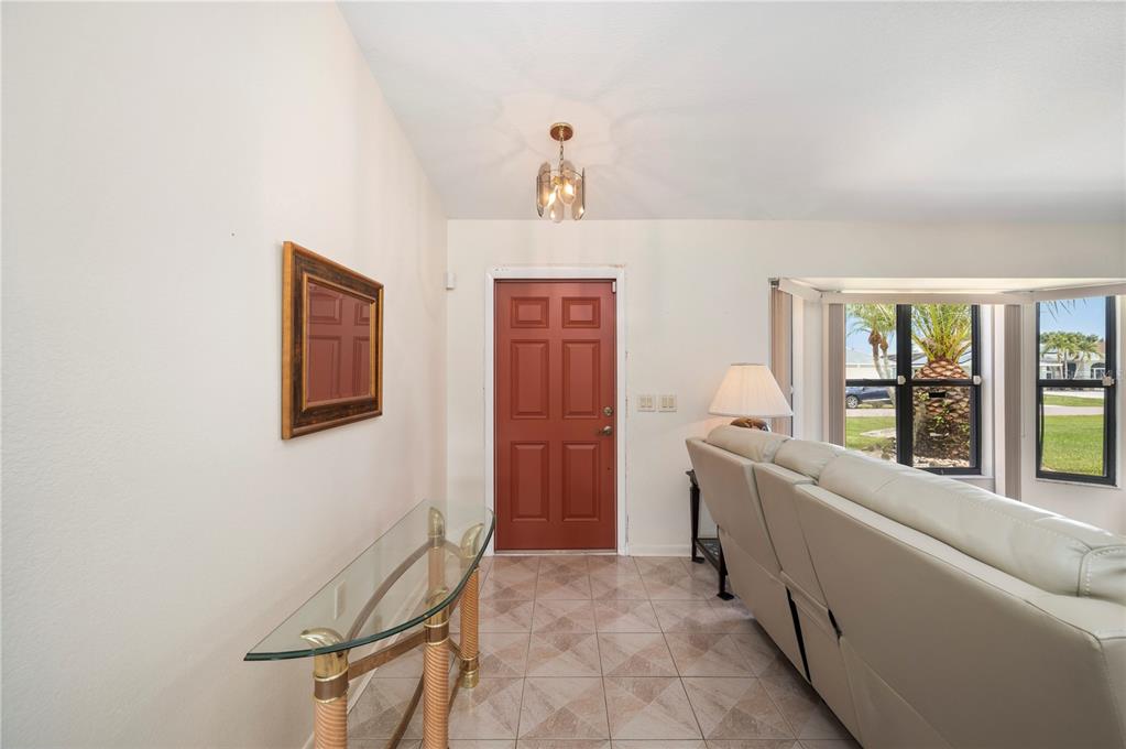 An entryway features a red front door, a glass console table, and tile flooring — 1659 BLUE LAKE CIRCLE, PUNTA GORDA, FL