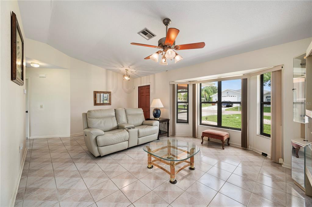 A living room features light tile floors, a beige leather sofa, and a bay window — 1659 BLUE LAKE CIRCLE, PUNTA GORDA, FL