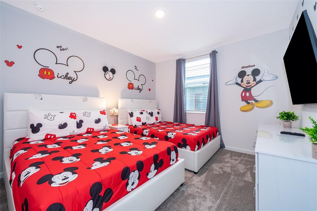A bedroom features two beds with Mickey Mouse bedding, themed wall decals, and a television — 8889 CABOT CLIFFS DRIVE UNIT 101, DAVENPORT, FL