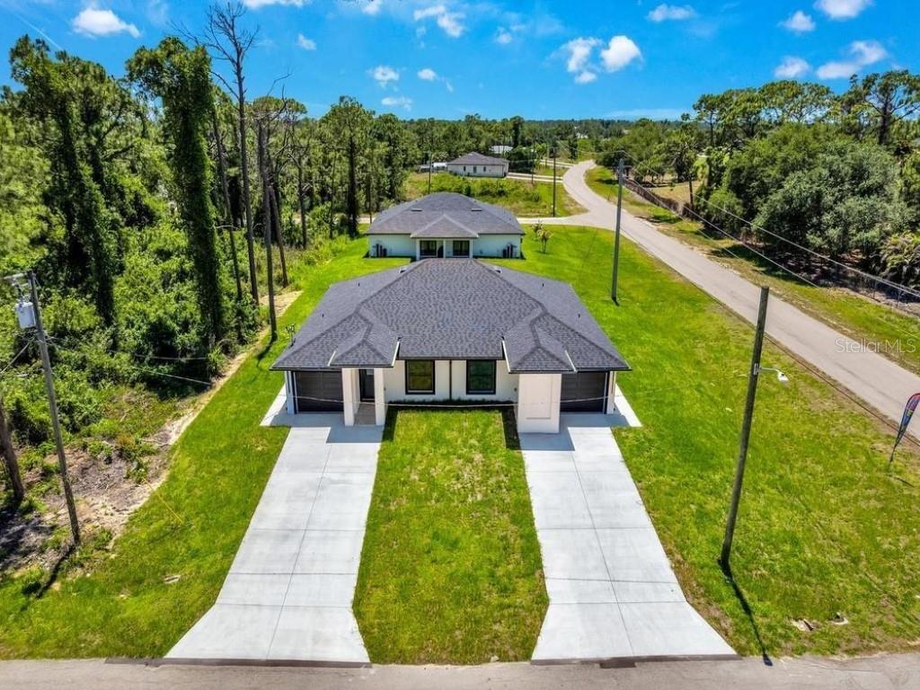 An aerial view of a duplex with two concrete driveways and a dark shingled roof — 4747 13TH STREET SW, LEHIGH ACRES, FL