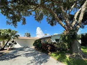 A single-story house with a white garage and a large tree in the front yard — 6901 GULF WINDS DRIVE, ST PETE BEACH, FL