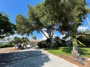 A single-story house with a gravel driveway, large shade tree, and palm tree in front — 6901 GULF WINDS DRIVE, ST PETE BEACH, FL