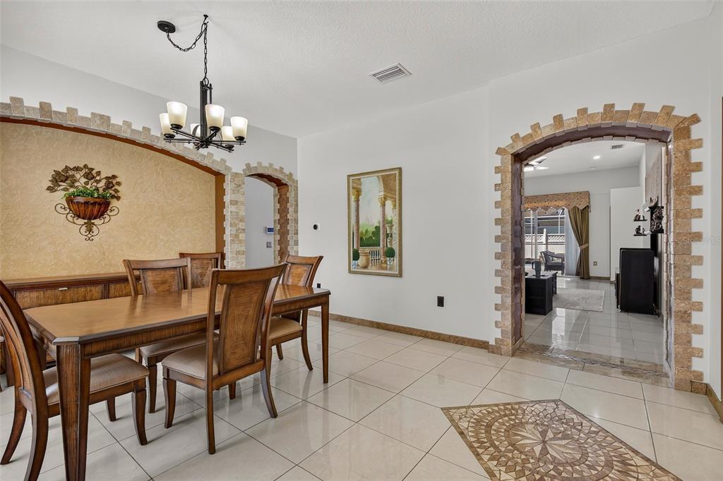 A dining room features tile floors, a wooden table, and decorative stone archway accents — 30524 LANESBOROUGH CIRCLE, WESLEY CHAPEL, FL
