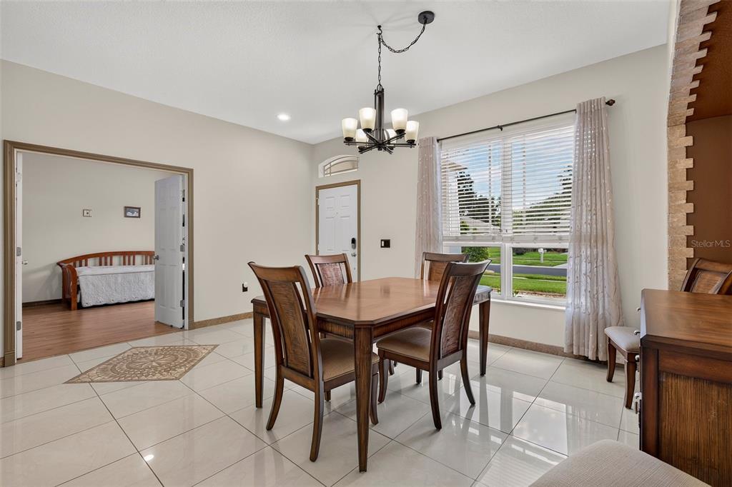 A dining room features a wooden table, four chairs, a chandelier, and light-colored tile flooring — 30524 LANESBOROUGH CIRCLE, WESLEY CHAPEL, FL