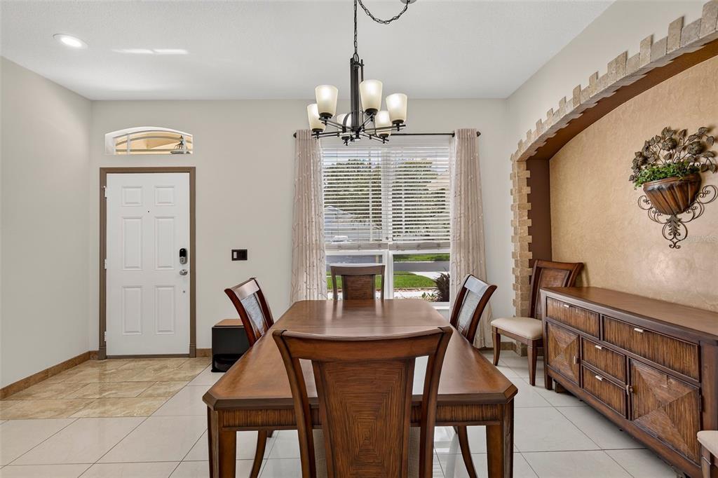 A dining room features a wooden table, chairs, a chandelier, and a built-in wall niche — 30524 LANESBOROUGH CIRCLE, WESLEY CHAPEL, FL