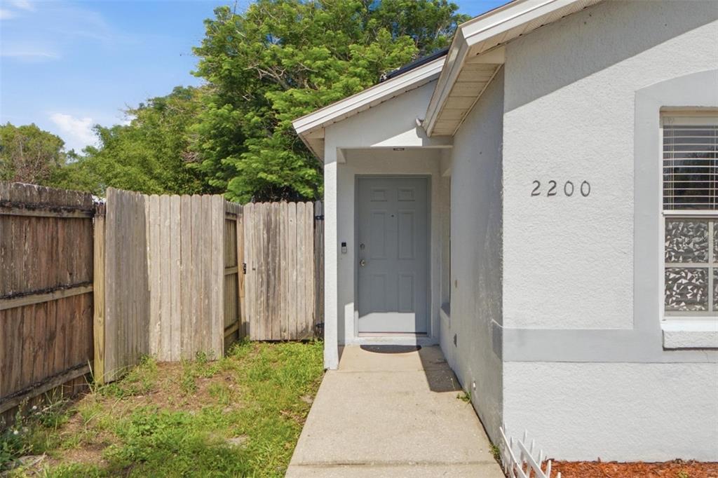 A concrete walkway leads to the front door of a house with a wooden fence — 2200 ROSE BROOK COURT, ORLANDO, FL