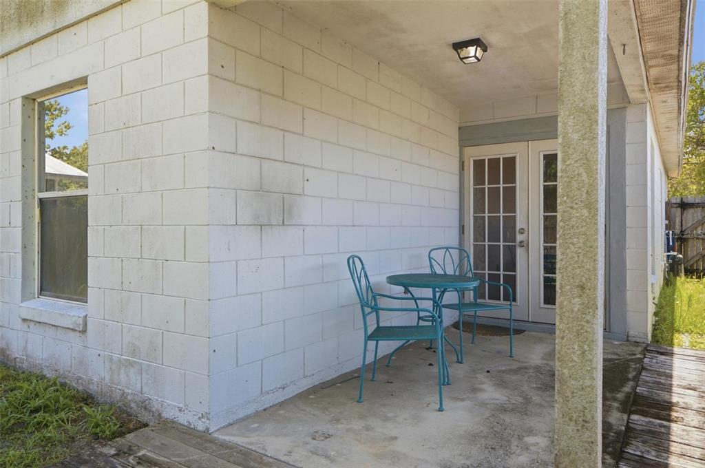 A covered concrete patio features a small metal table and two chairs against a block wall — 2200 ROSE BROOK COURT, ORLANDO, FL
