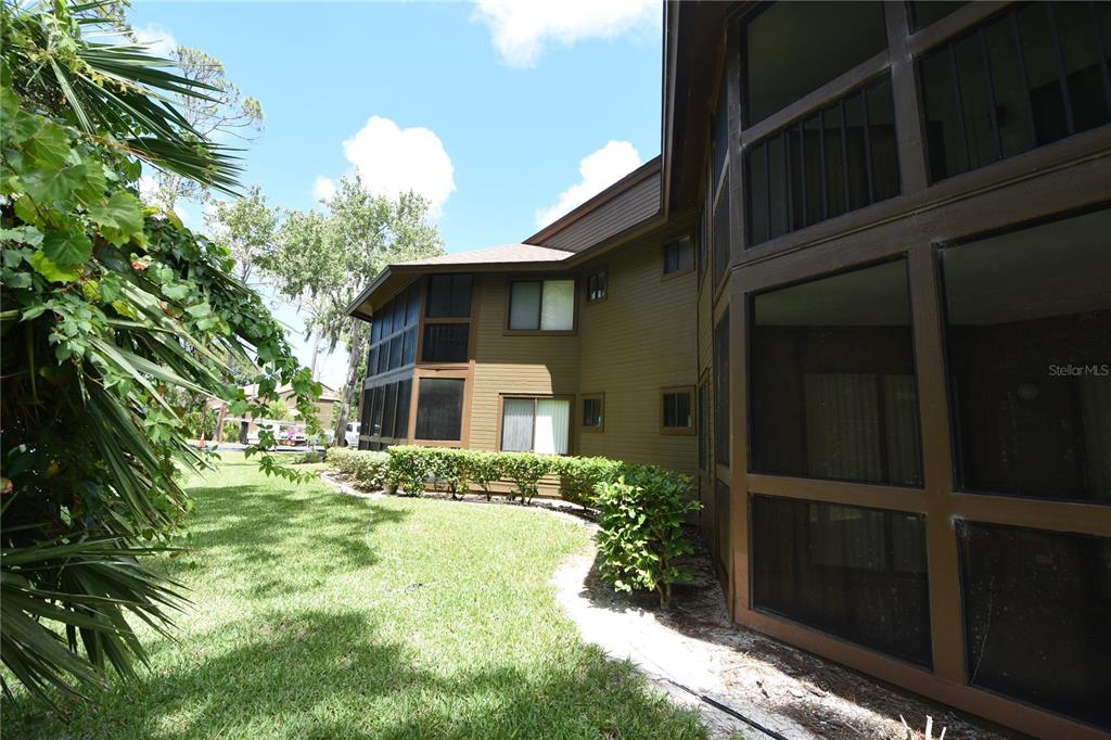 A multi-story building with brown siding and screened-in porches overlooks a grassy lawn — 4 SOUTHBURY COURT UNIT 4, PALM COAST, FL