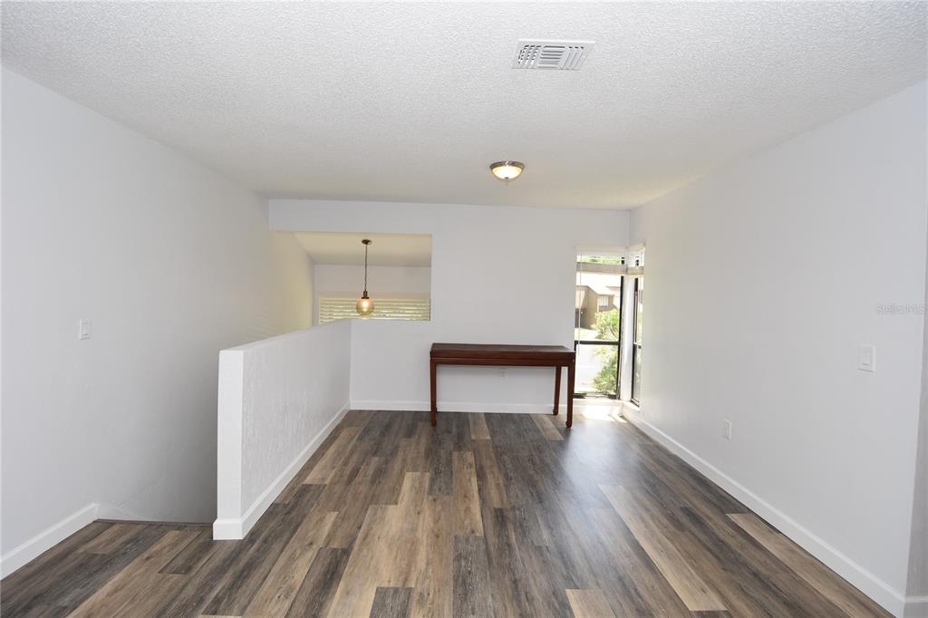 An empty room with wood-look flooring, a half wall, a console table, and a window — 4 SOUTHBURY COURT UNIT 4, PALM COAST, FL