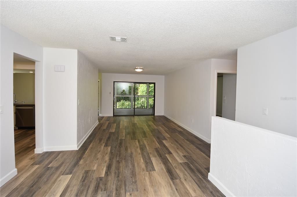 An empty living area features wood-look flooring, white walls, and a sliding glass door — 4 SOUTHBURY COURT UNIT 4, PALM COAST, FL