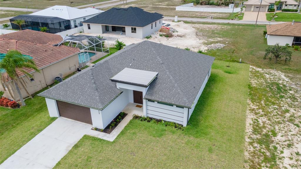 An aerial view shows a modern single-story house with a gray roof and attached garage — 1638 NW 36TH PLACE, CAPE CORAL, FL