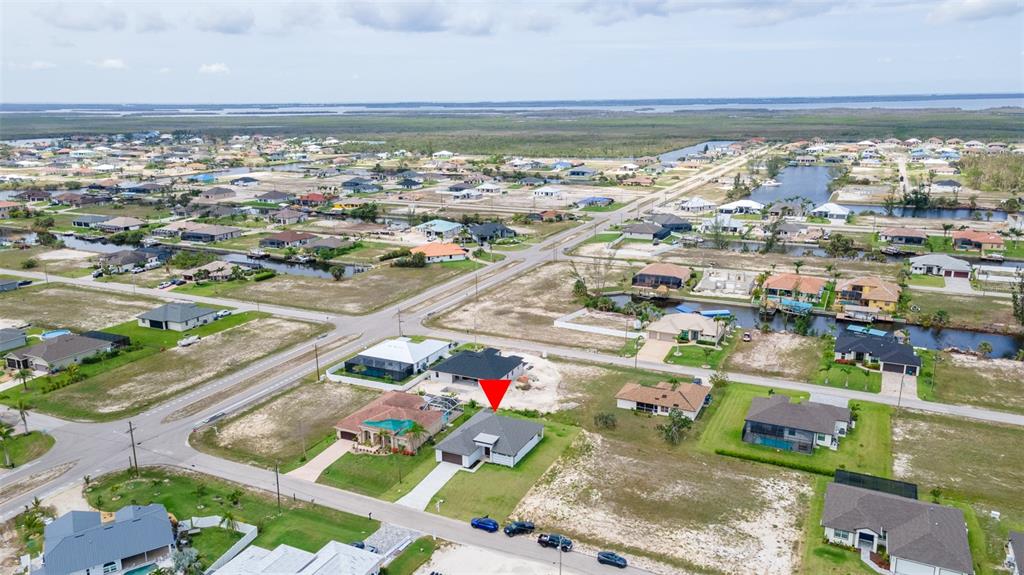 An aerial view shows a single-family house marked with a red arrow in a neighborhood — 1638 NW 36TH PLACE, CAPE CORAL, FL
