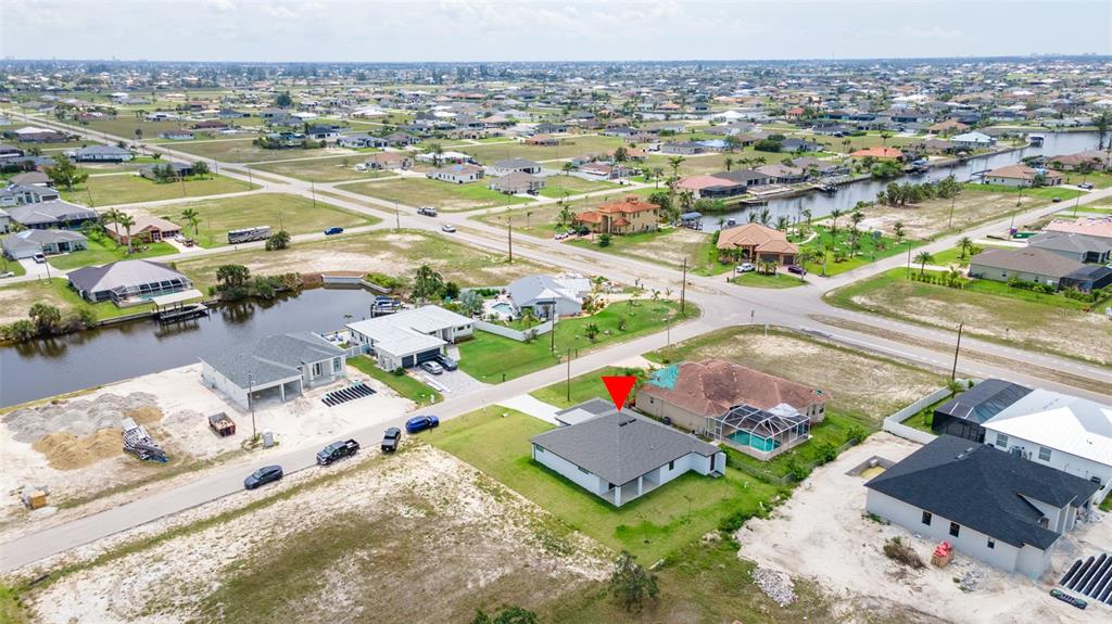 An aerial view shows a residential neighborhood with a single-story house marked by a red arrow — 1638 NW 36TH PLACE, CAPE CORAL, FL