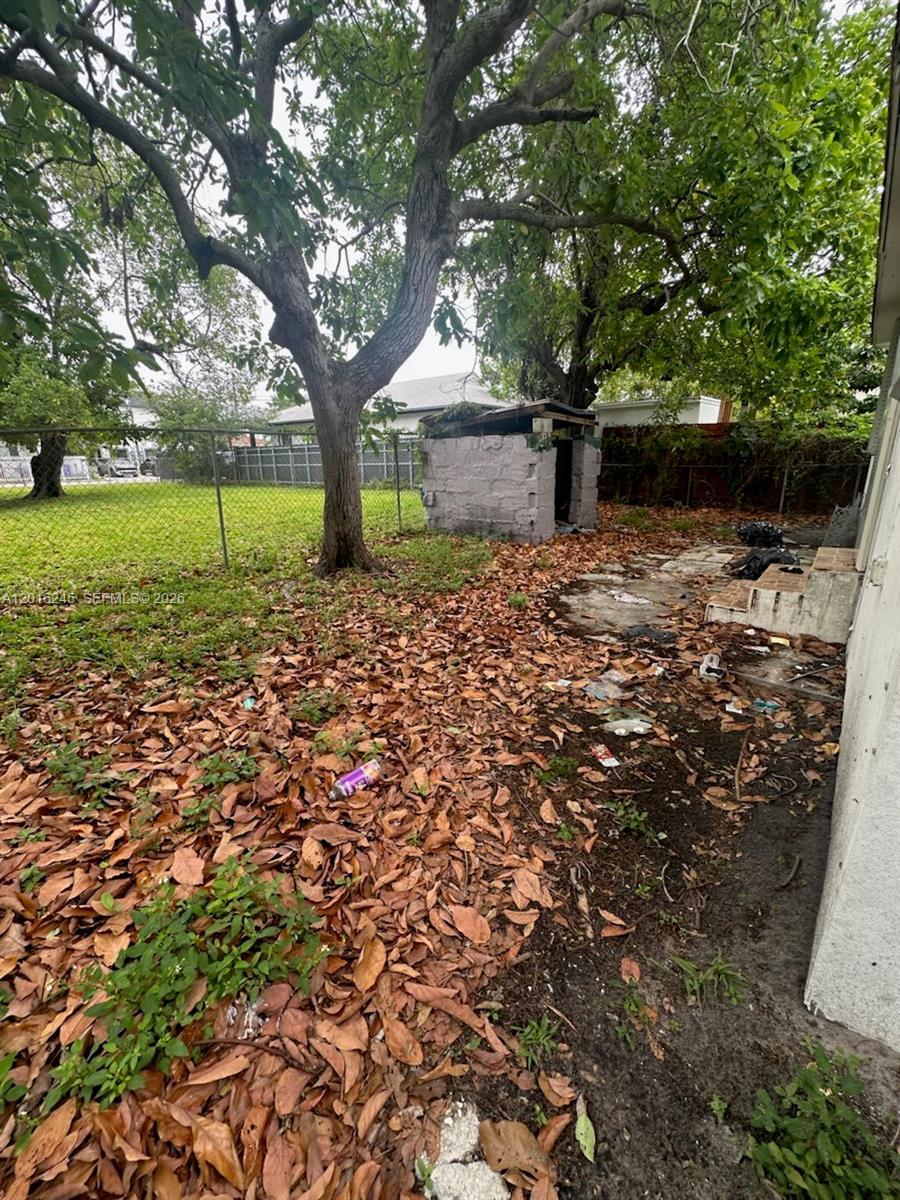 A backyard features a concrete block shed, a large tree, and scattered fallen leaves — 1891 NW 62nd Ter, Miami FL 33147, MIAMI, FL