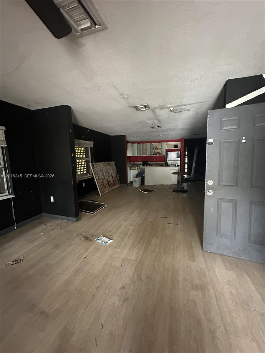 An open-concept living area features black walls, light wood-look flooring, and a kitchen in the back — 1891 NW 62nd Ter, Miami FL 33147, MIAMI, FL